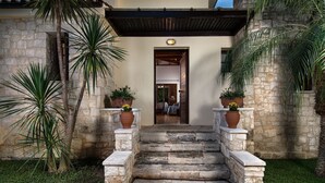 A stone staircase leading to a door, flanked by potted plants and palm trees. - Koukounari luxury villa with pool. A timeless paradise!  (Chania)