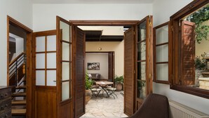 A room with a wooden door leading to a patio area with a table and chairs, a sofa, and a radiator. - Koukounari luxury villa with pool. A timeless paradise!  (Chania)