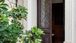A traditional entrance with a decorative metal door, a stone wall, and a potted plant. - [Le Grand Bleu] - Villa Maremonti Taormina (Taormina)