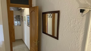 A hallway with a wooden door, a framed mirror, and a wall-mounted electrical outlet.
