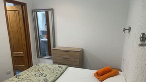 A bedroom with a bed, a wooden dresser, a window, and a door.