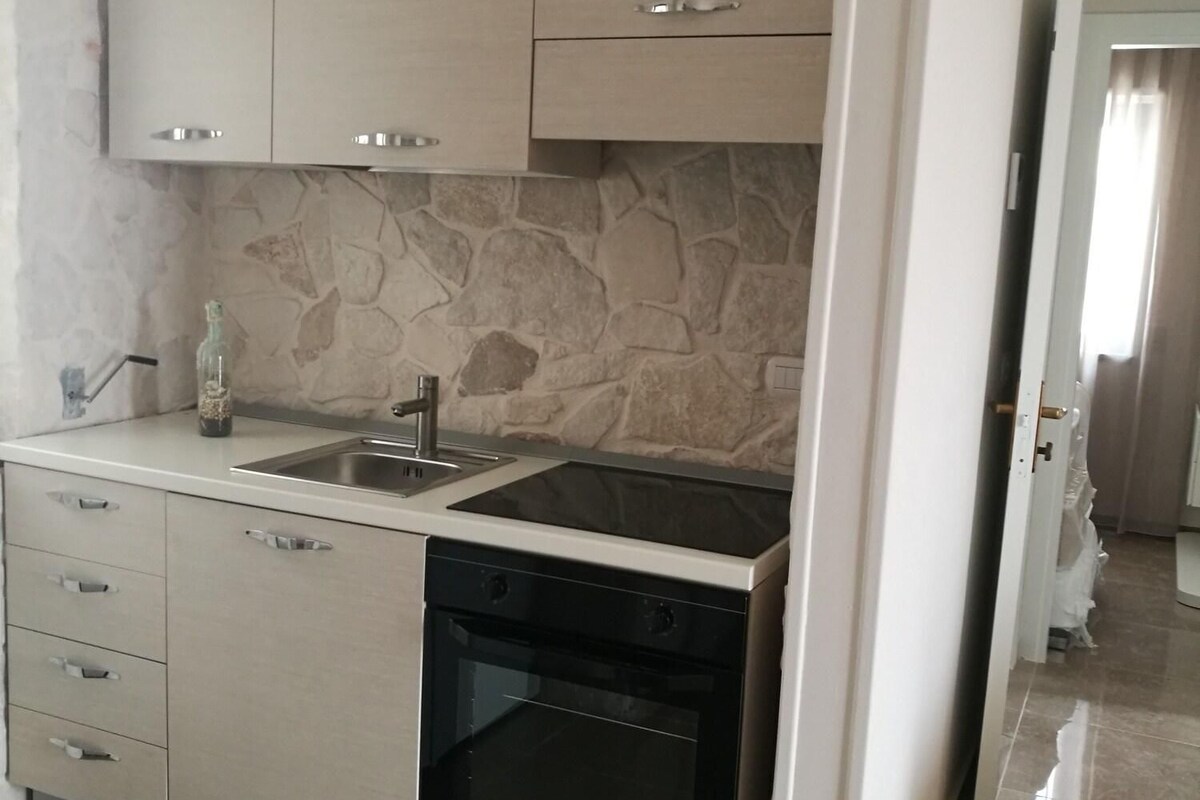 A modern kitchen with a built-in oven, a dishwasher, and a stone backsplash.