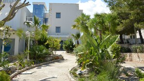 A pathway leading to a building with a blue door and a sign that reads "RESIDENCE". - La Corvetta (Monopoli)