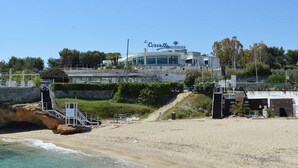 A beachfront hotel with a visible name sign, a sandy beach, and a clear blue sky. - La Corvetta (Monopoli)