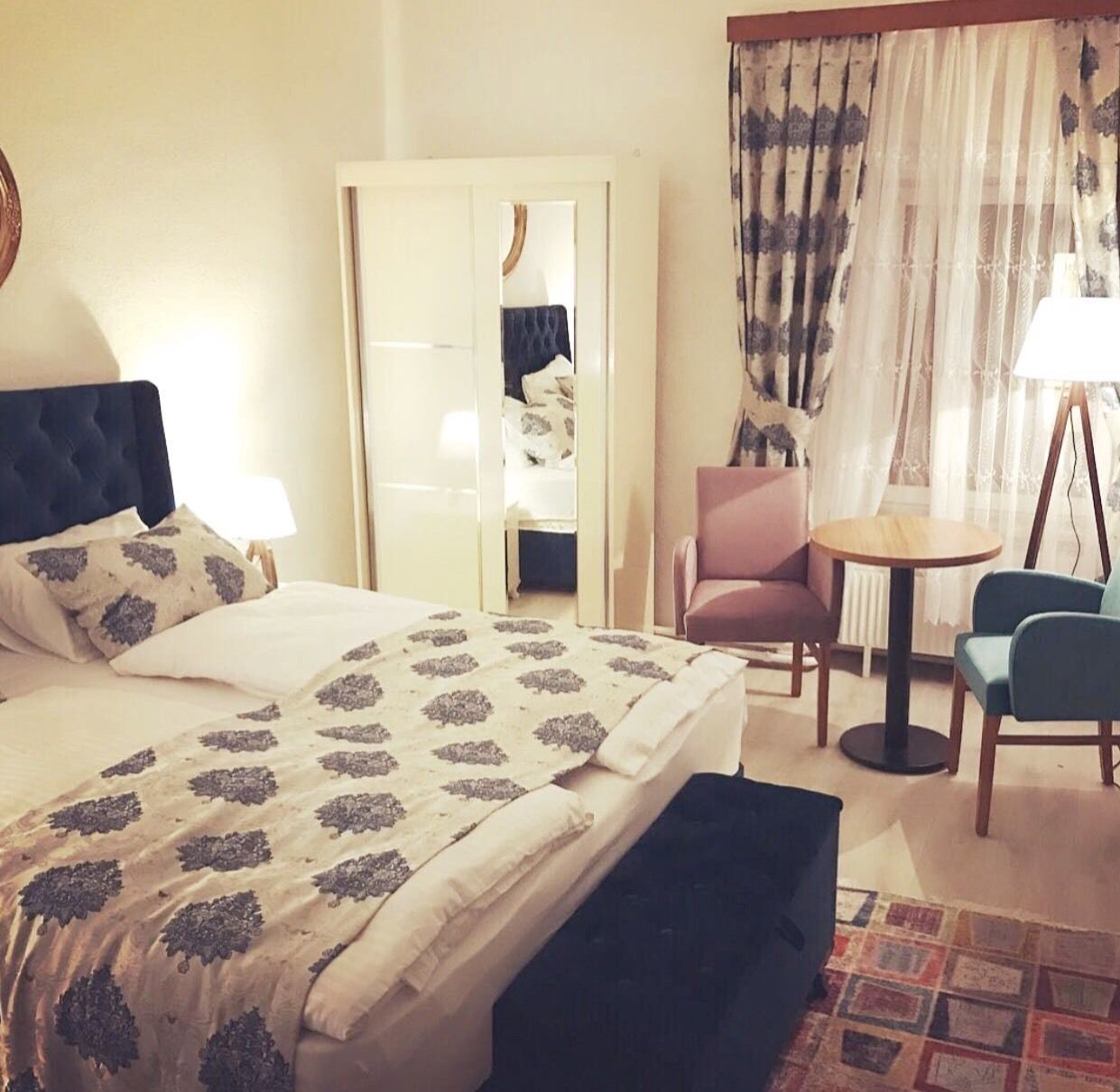 Una habitación de hotel con una cama, una silla, una mesita y un espejo.