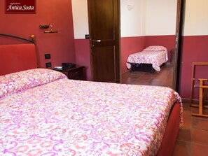 Een hotelkamer met een groot bed, een nachtkastje, een stoel en een deur naar een andere kamer.
