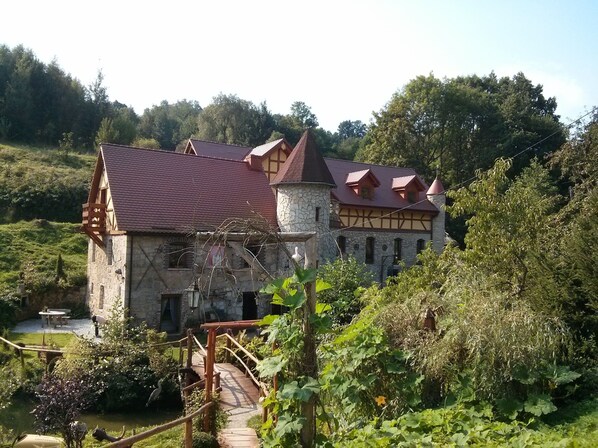 A stone building with a red-tiled roof and a wooden balcony.