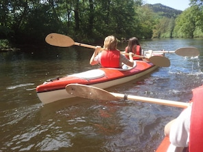 Two people in a red canoe on a river surrounded by trees.