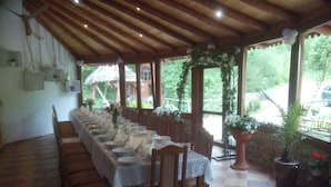 A long dining table set for a meal, with chairs on both sides, under a wooden ceiling with hanging lights. - Zbójna Debra (Lubomierz)