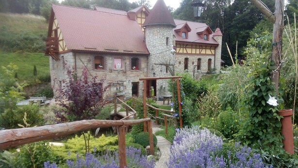 A stone building with a red roof and a wooden staircase leading to a door. - Zbójna Debra (Lubomierz)