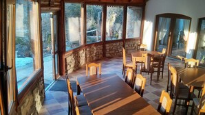 A dining area with a wooden table and chairs, stone walls, and large windows. - Zbójna Debra (Lubomierz)