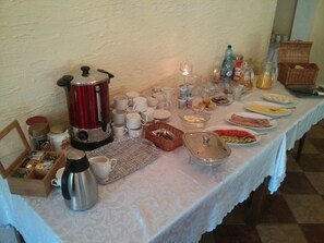 A breakfast buffet with various food items, cups, and a coffee maker.