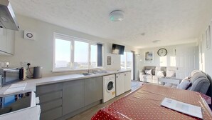 Cocina compacta con lavabo, lavadora y comedor con mesa.