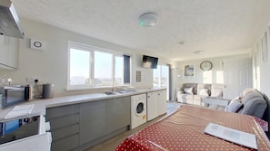 A compact kitchen with a sink, a washing machine, and a dining area with a table.