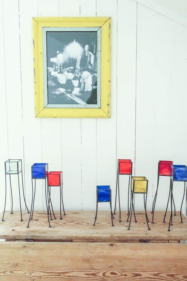 Una habitación con una pared de madera blanca, una fotografía blanco y negro enmarcada y una plataforma de madera con sillas coloridas.