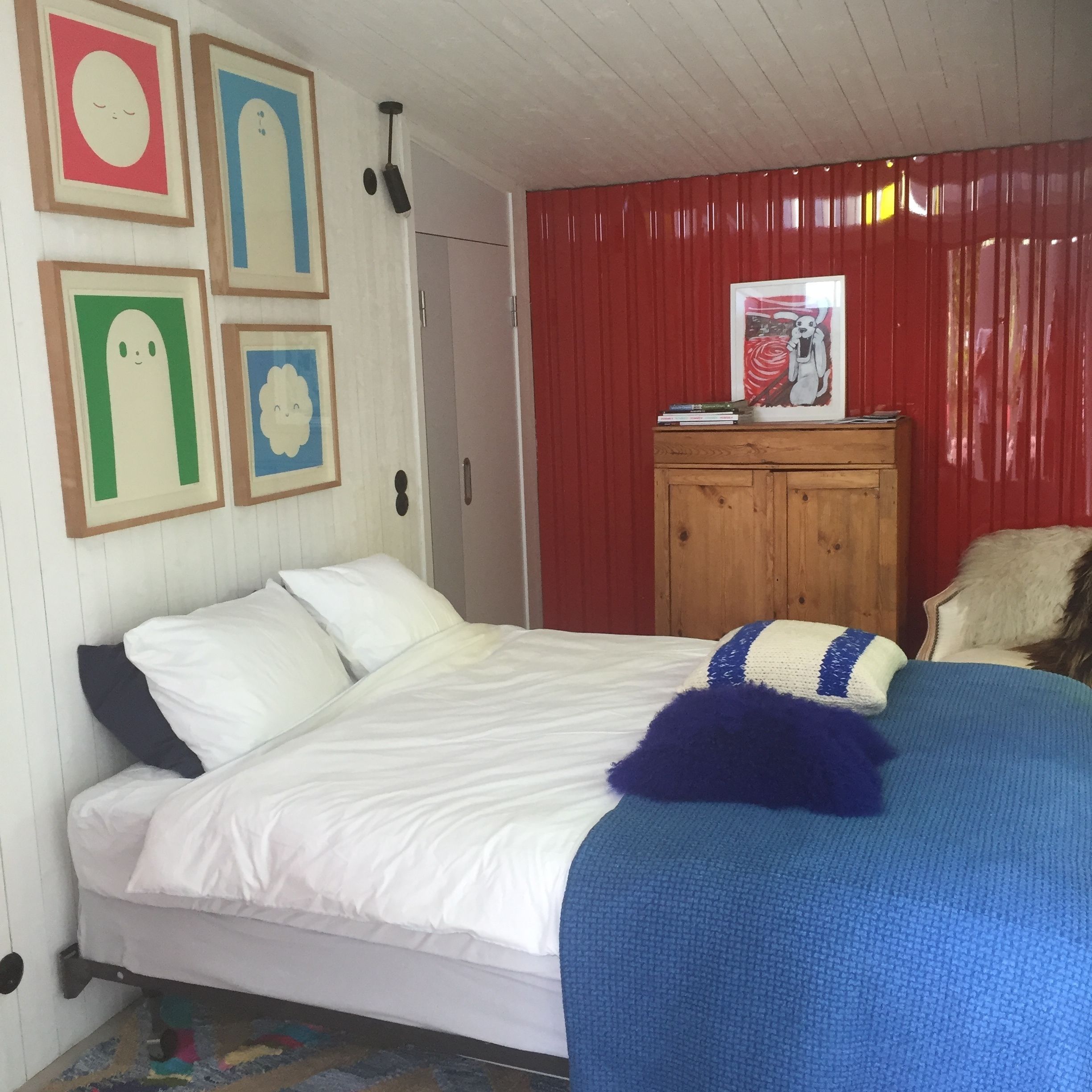 Een slaapkamer met een bed, een houten kast en wanddecoraties in lijsten.