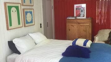 Een slaapkamer met een bed, een houten kast en wanddecoraties in lijsten.