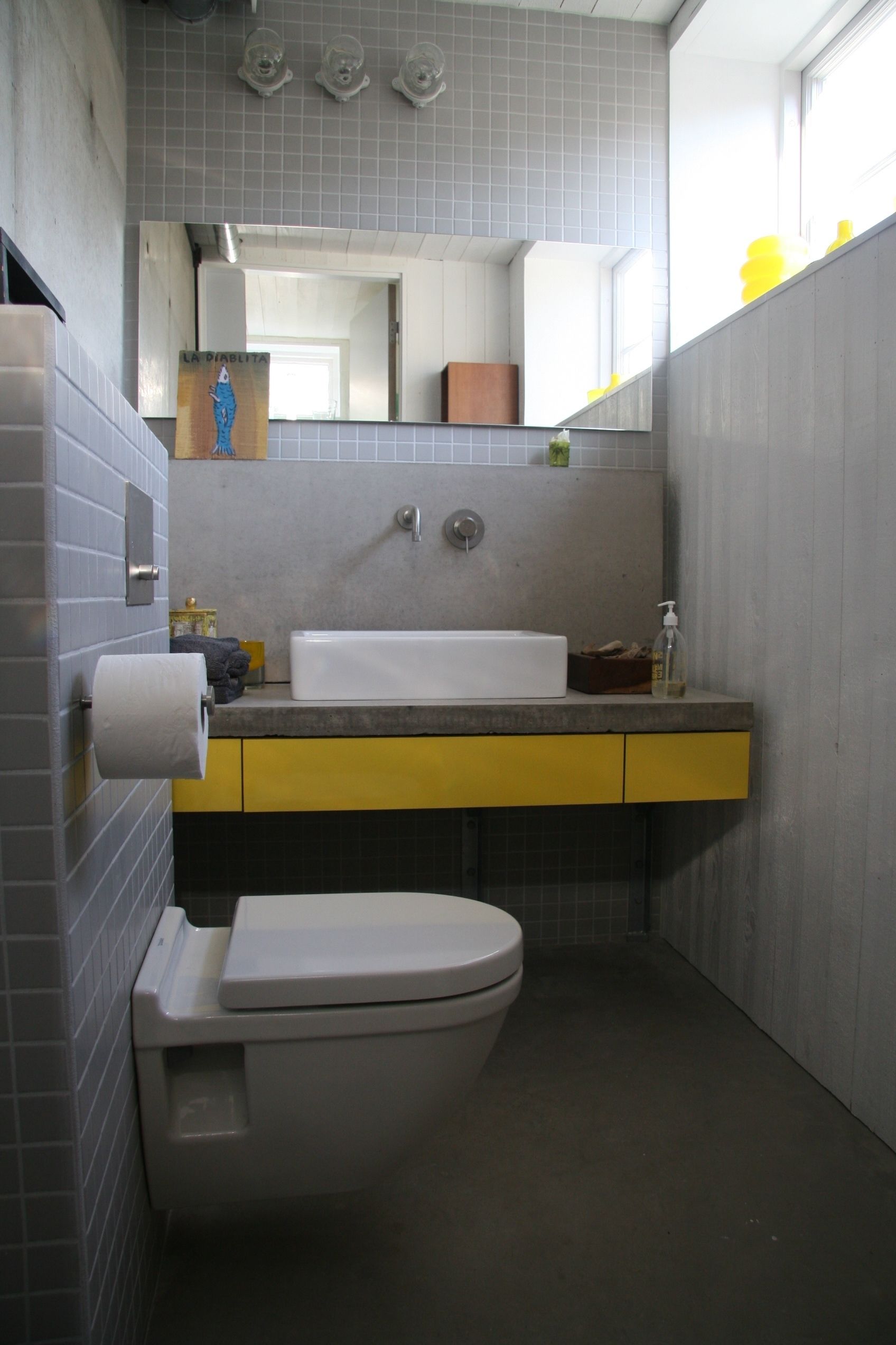 Een badkamer met toilet, wastafel en spiegel.