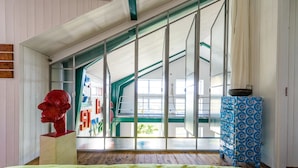 A room with a sloped ceiling, a large window, and a colorful wall decoration. - Lådfabriken (Hälleviksstrand)