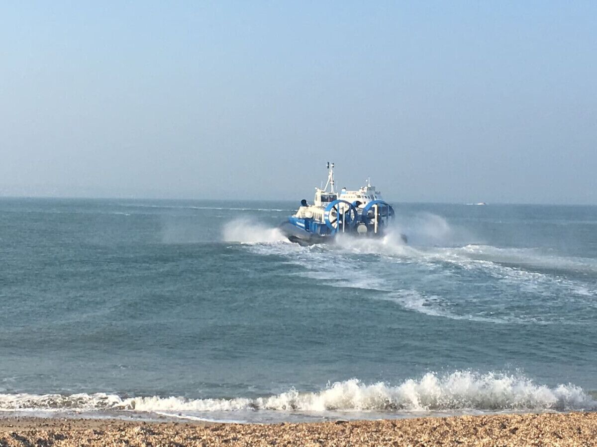 A blue boat with two people on it, moving through the water.