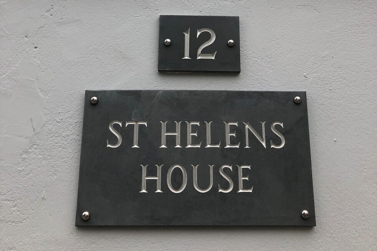 Ein Schild an einem Haus mit der Nummer 12 und dem Schriftzug 'ST HELENS HOUSE'.