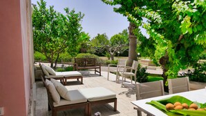 An outdoor patio with lounge chairs and a table, surrounded by greenery and trees. - Beautiful Villa with pool in the green of Salento, 110 sqm, quiet and luxurious (Cutrofiano)