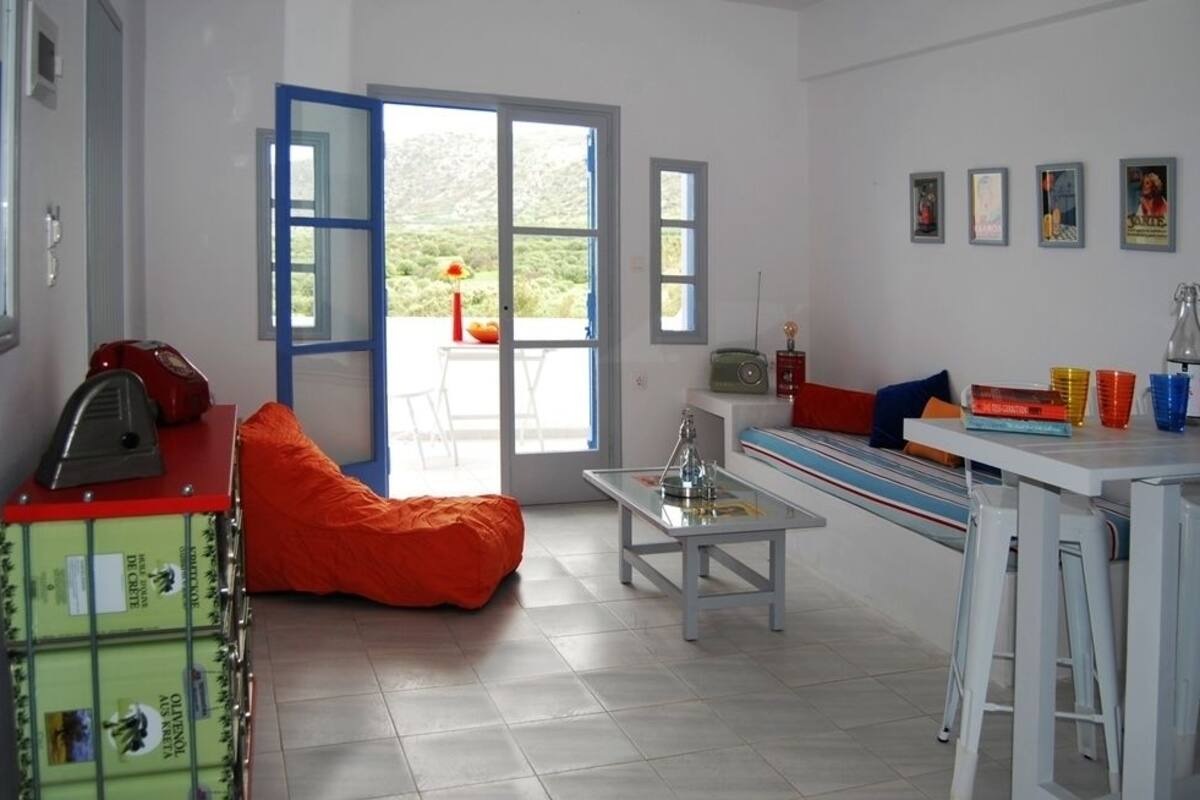 Una cocina luminosa con un ventanal grande, un radiador rojo y un armario verde.