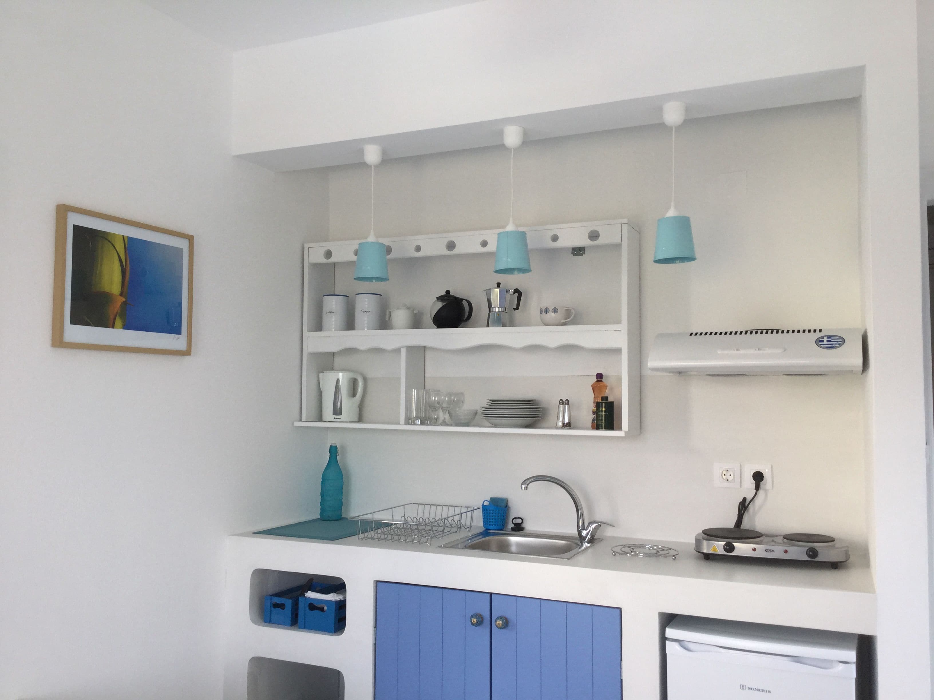 A modern kitchen with white cabinets, blue accents, a sink, and a compact dishwasher.