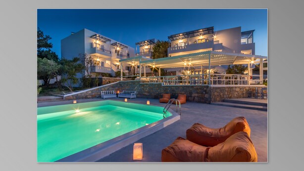Ein modernes Hotel mit Pool auf dem Dach und einer Außen-Sitzgelegenheit.