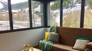 Una habitación con un ventanal grande, un sofá marrón, una mesita de madera y un farol.