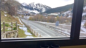 Vista desde una ventana sobre un camino, con una montaña al fondo.