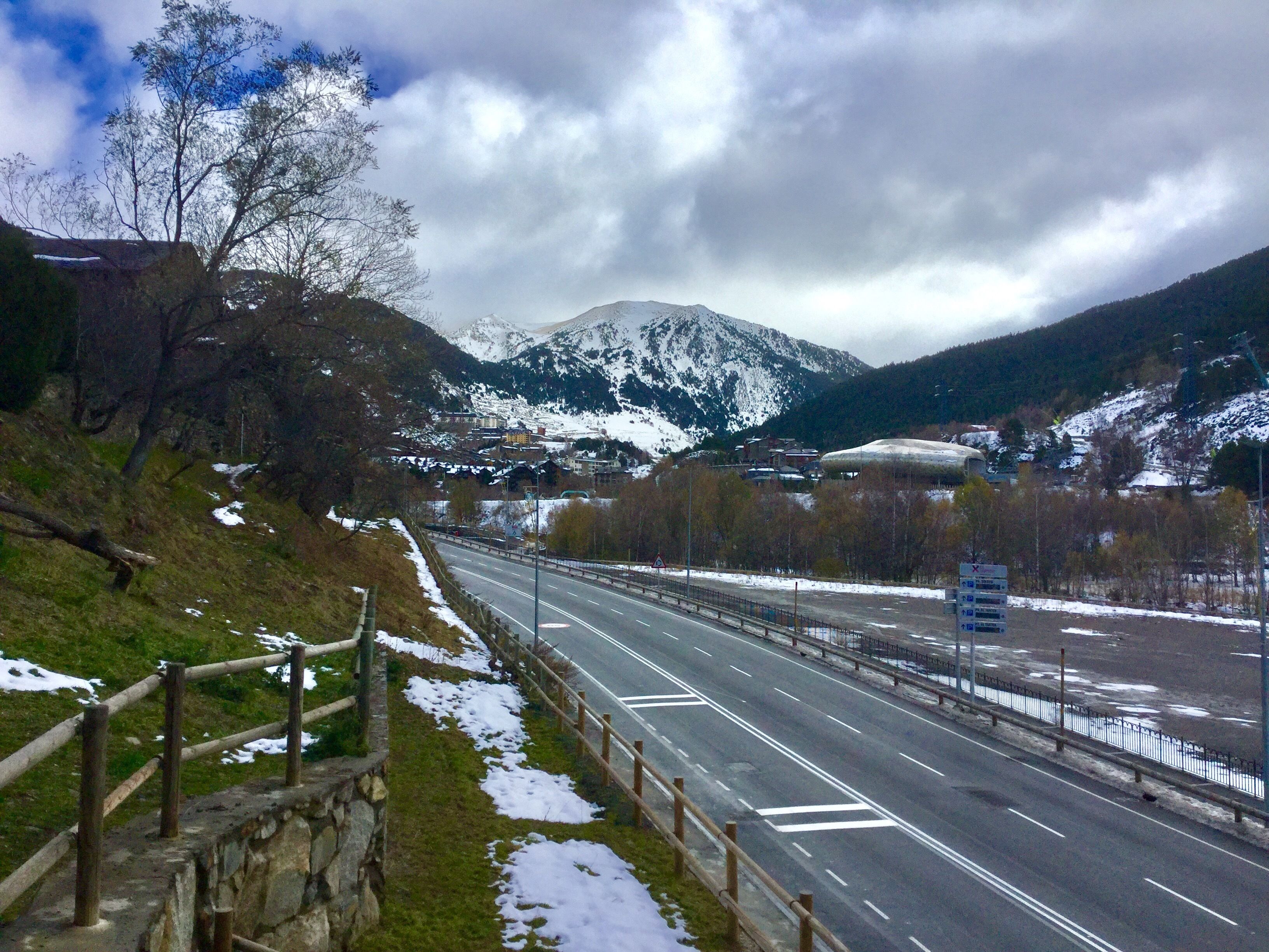 A highway with snow on the sides and mountains in the background.