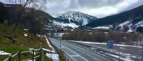 A highway with snow on the sides and mountains in the background.