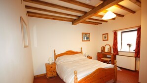 A bedroom with a wooden bed, a nightstand, a dresser, and a window with curtains. - The Granary at Todds House Farm  (Stockton on Tees)