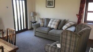 A living room with a grey sofa, plaid armchairs, a small table, and a lamp. - The Granary at Todds House Farm  (Stockton on Tees)