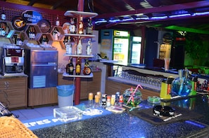 A bar area with shelves of liquor bottles, a refrigerator, and a coffee machine.