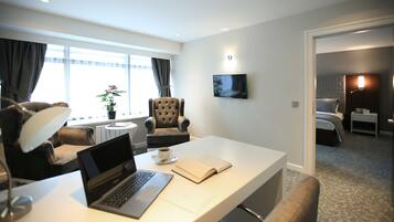 Habitación de hotel con escritorio, computadora portátil y planta en maceta.