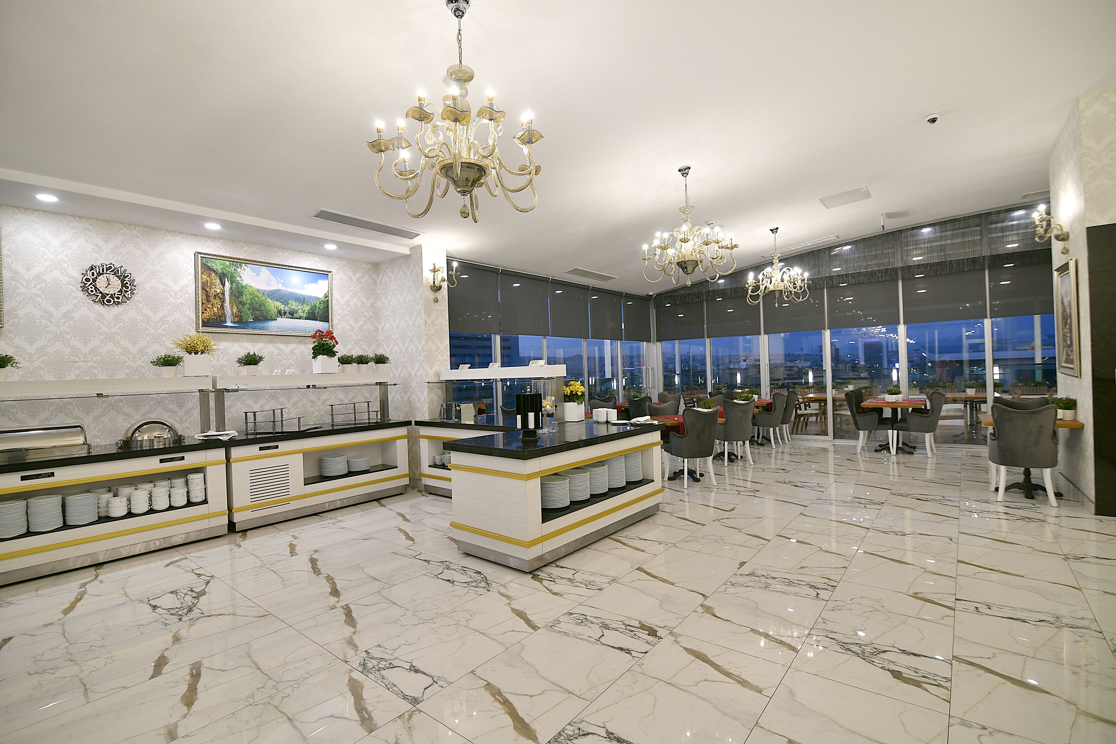 A modern hotel lobby with a marble floor, a central bar area, and large windows offering a city view.