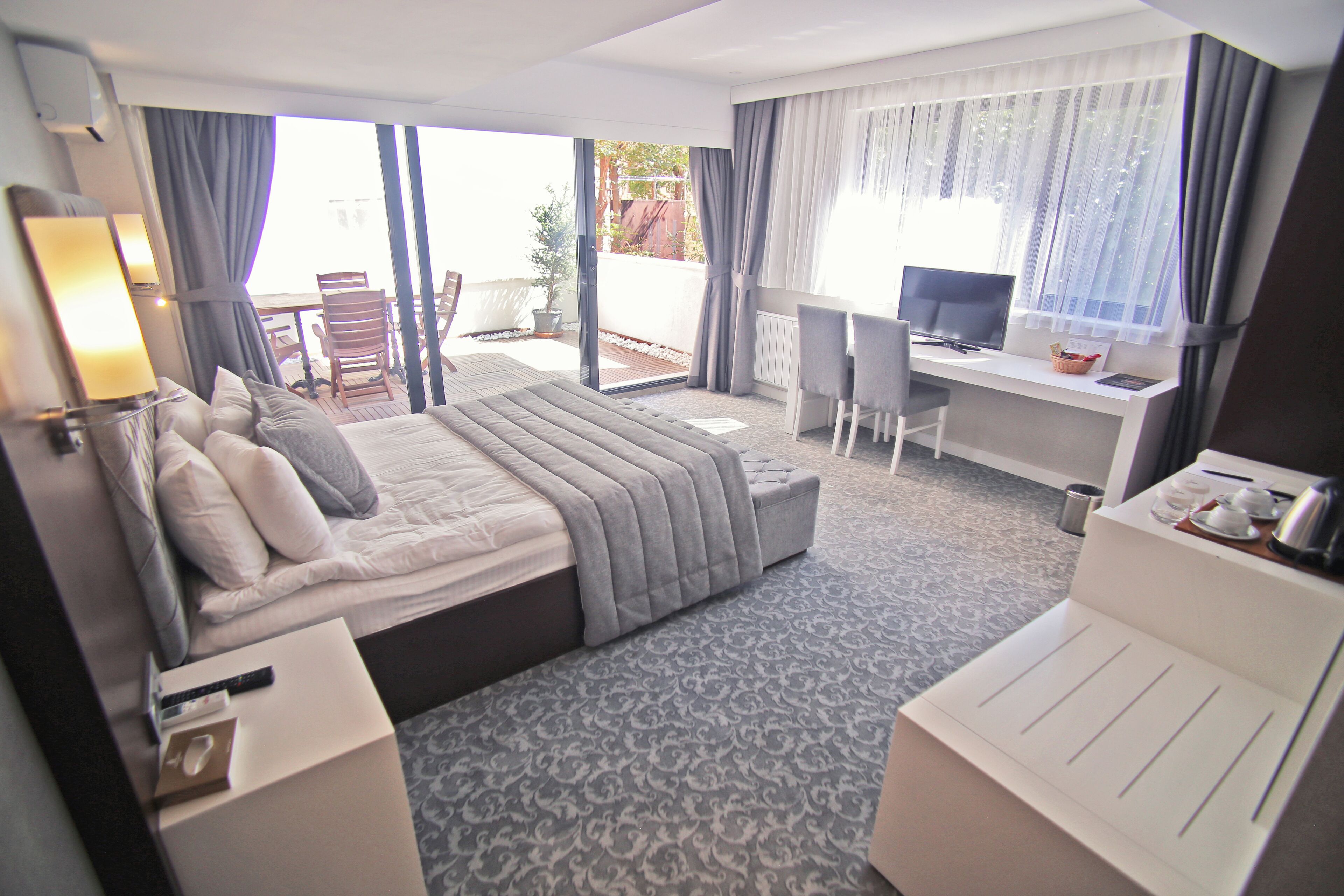 Una habitación de hotel con cama, escritorio, silla y balcón con mesa y sillas.