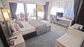 Una habitación de hotel con cama, escritorio, silla y balcón con mesa y sillas.