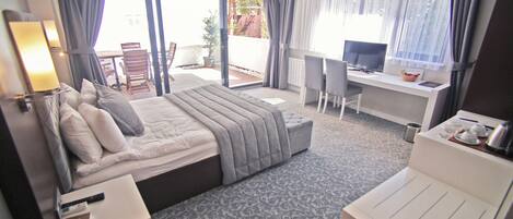 Una habitación de hotel con cama, escritorio, silla y balcón con mesa y sillas.
