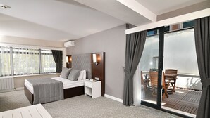 Quarto de hotel com cama, mesa de cabeceira e vista para a varanda.