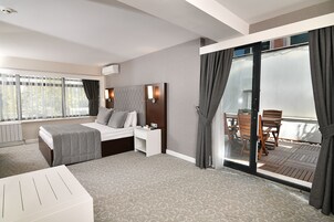 Una habitación de hotel con cama, mesita de noche y vistas al balcón.
