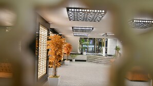 Um hall de entrada com balcão de recepção, plantas em vasos e teto com padrão.