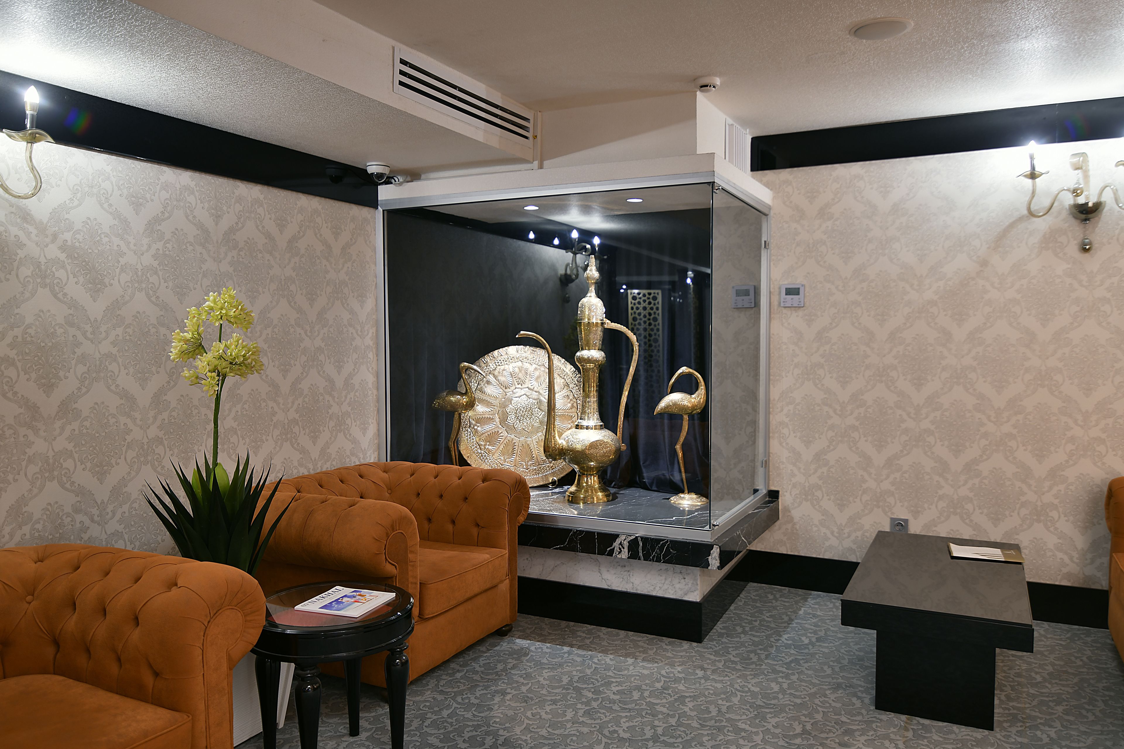 A lobby with a tufted sofa, a small table, and a decorative display case with ornate items.