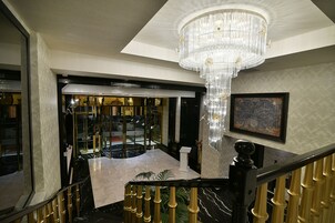 Una gran escalera con candelabro, suelo de mármol y vistas a un restaurante o comedor.