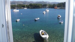 Una marina con diverse imbarcazioni ormeggiate, acqua cristallina e un paesaggio montuoso sullo sfondo.