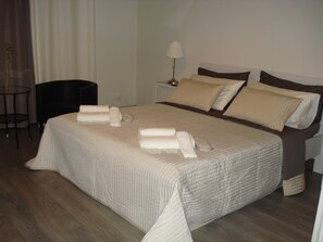 A neatly made bed with pillows and towels, a bedside table with a lamp, and a chair in a hotel room.