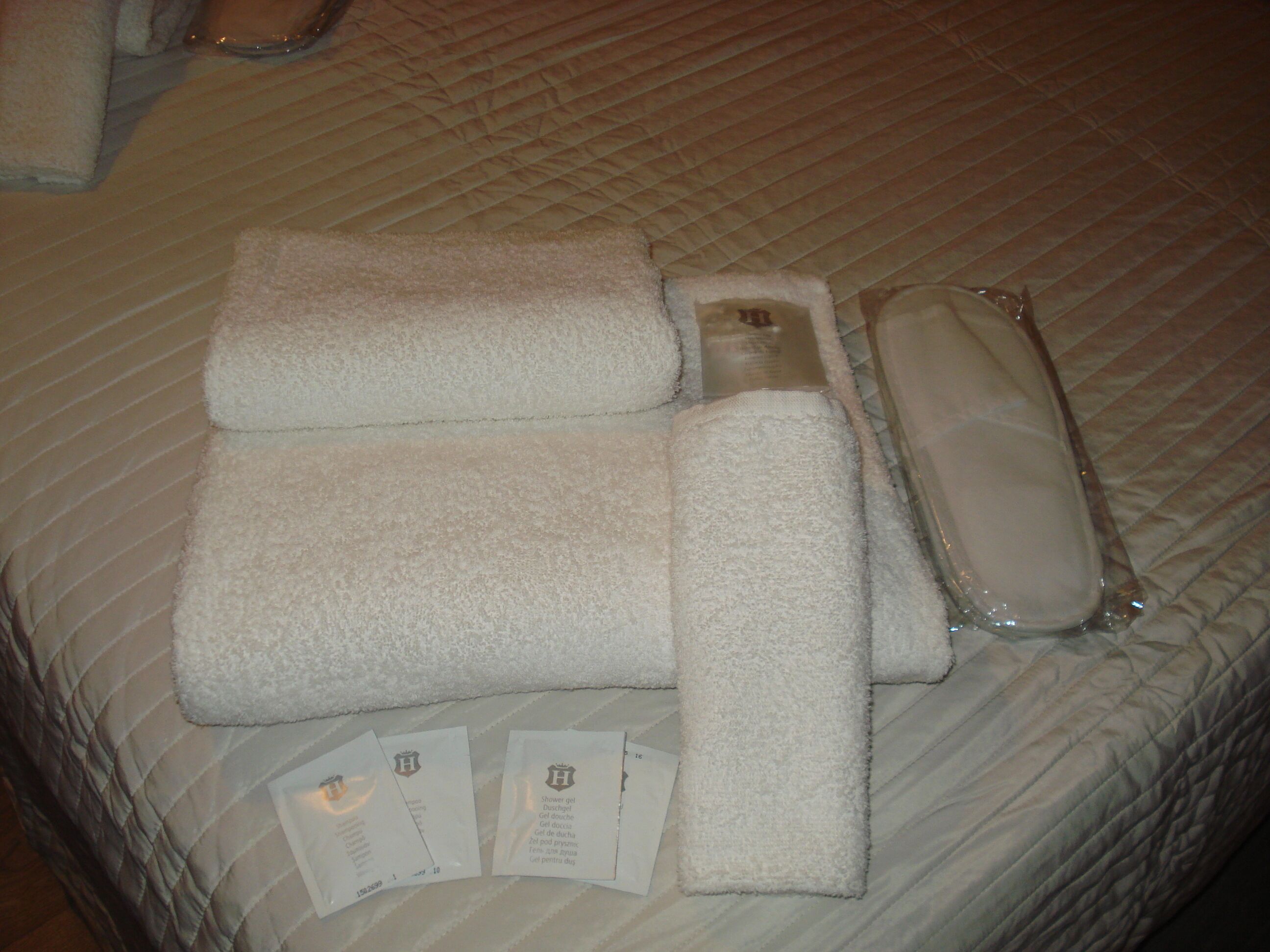 A bed with neatly folded towels, a bathrobe, and a set of toiletries on a bed with a striped pattern.