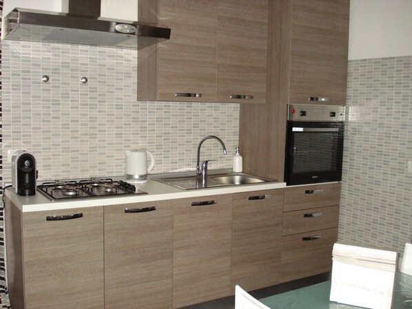 A modern kitchen with a gas stove, stainless steel sink, and built-in oven.